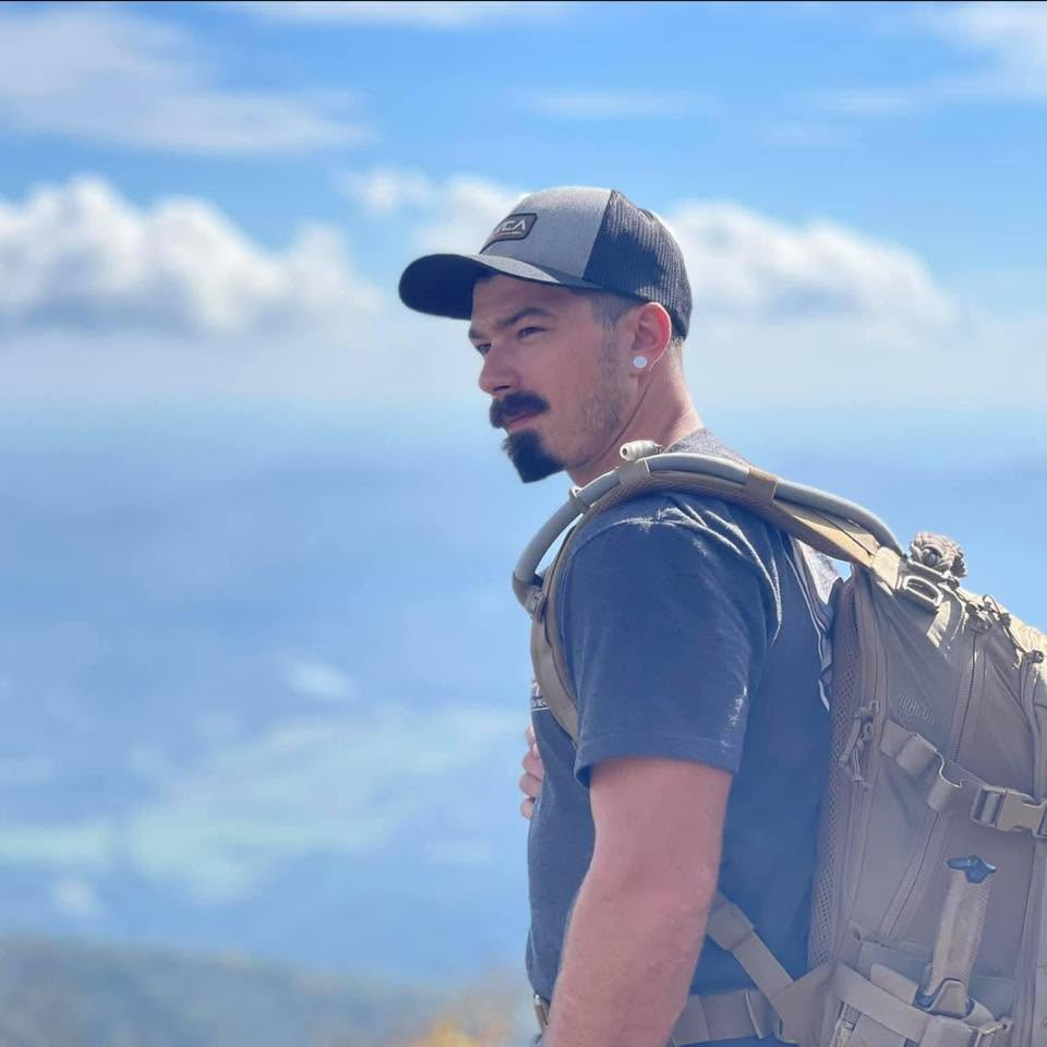 Trey Hewitt outdoors wearing a cap and backpack